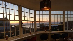 A room with large windows, a hanging light fixture, and several chairs. - Hotel Sandvig Havn (Allinge)