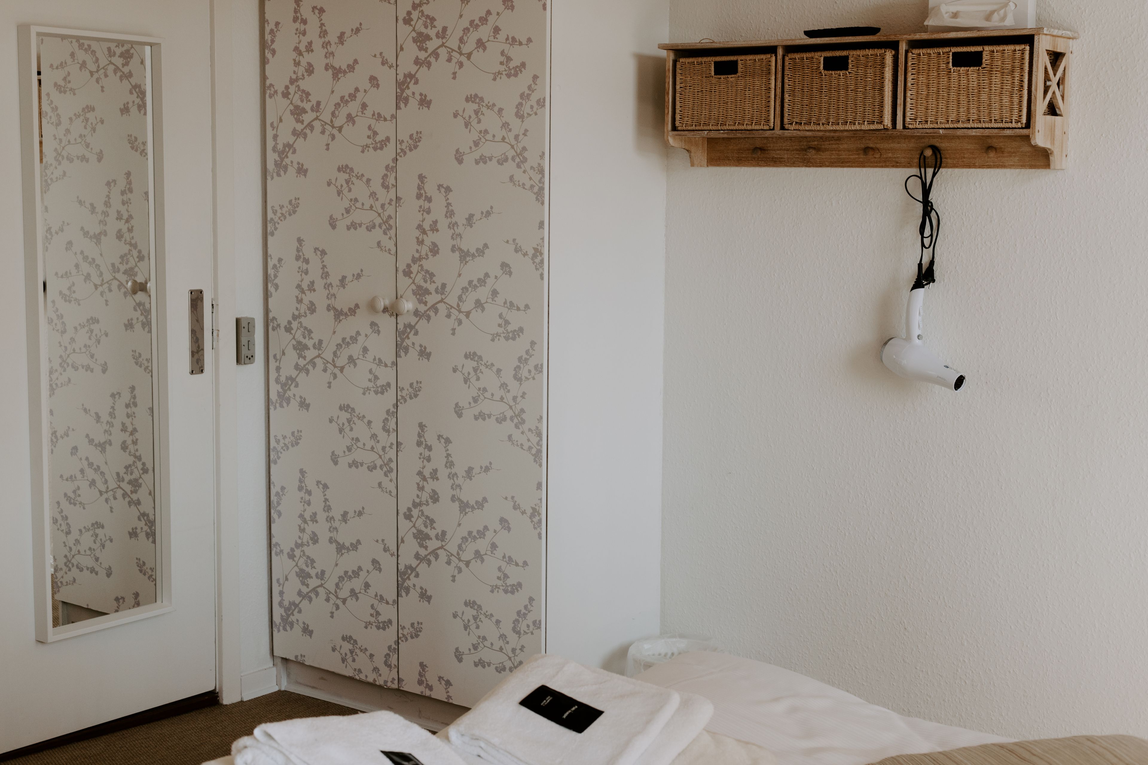 Une chambre à coucher avec un lit, une armoire et une étagère avec des paniers.