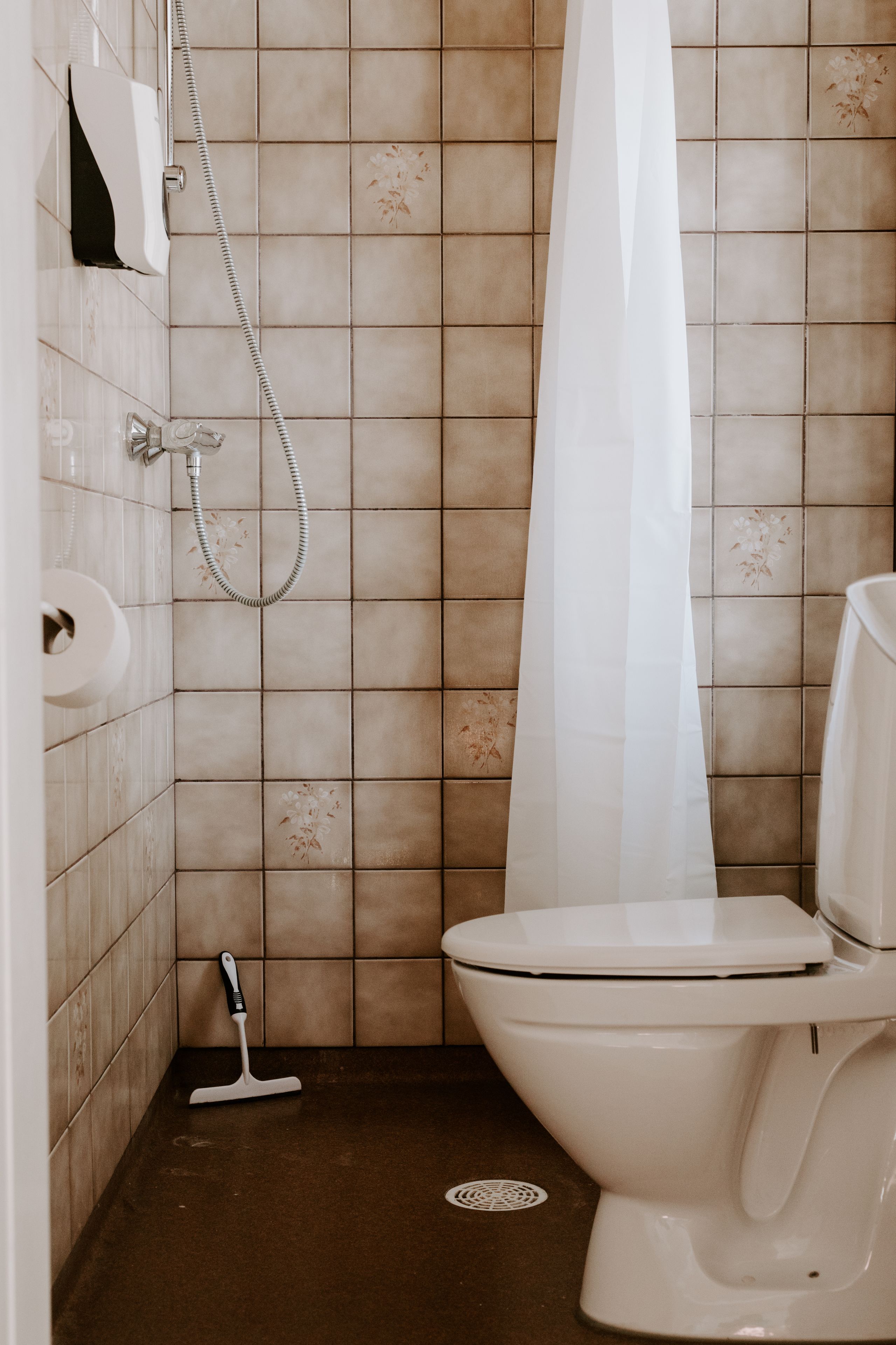 A bathroom with a toilet, a shower, and a hand dryer.