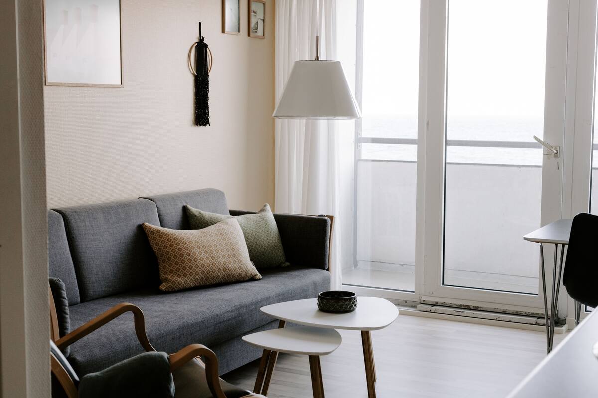 A modern living room with a grey sofa, a small round table, and a black chair.