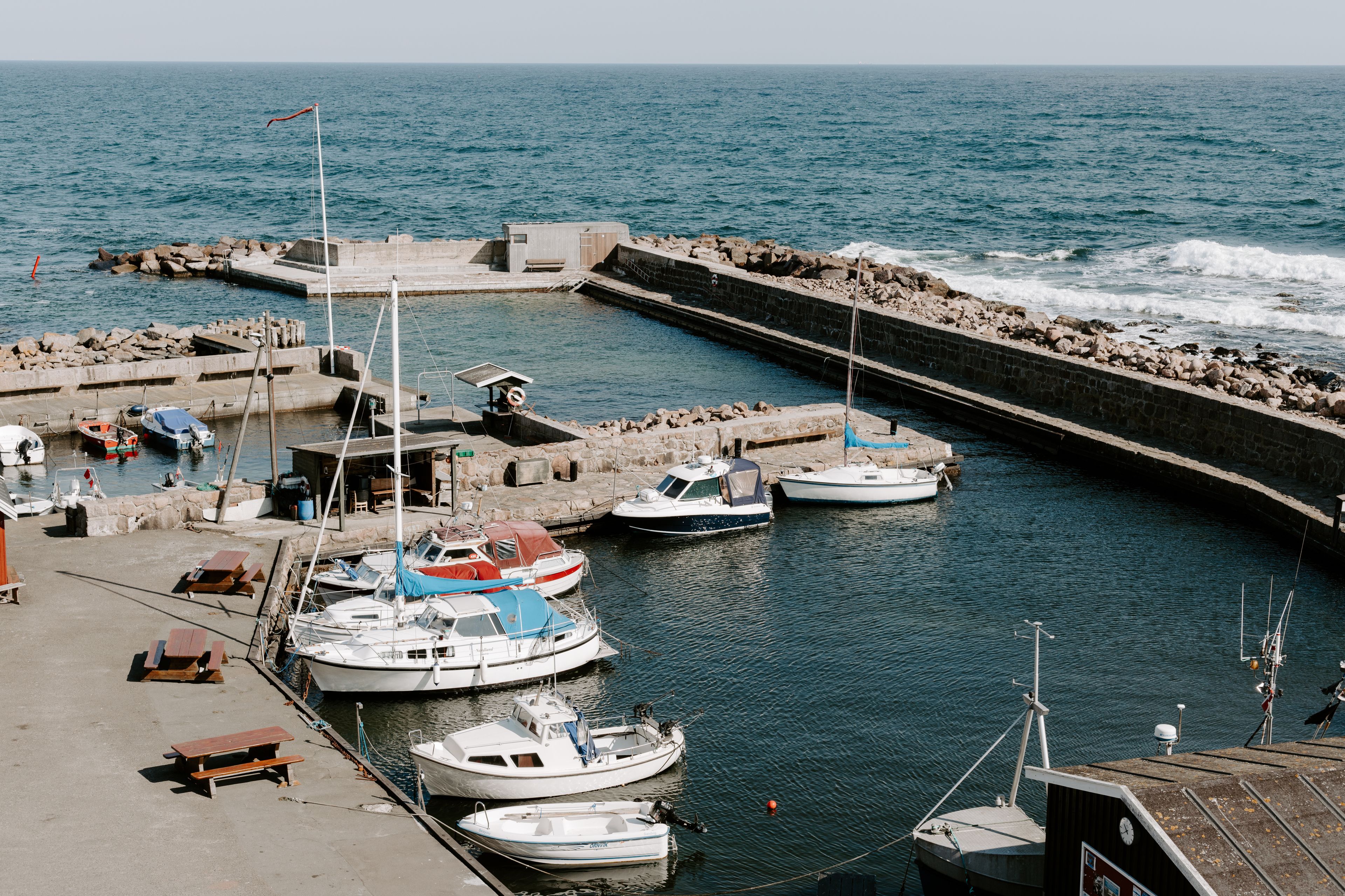 A marina with boats docked, a pier, and a small building.