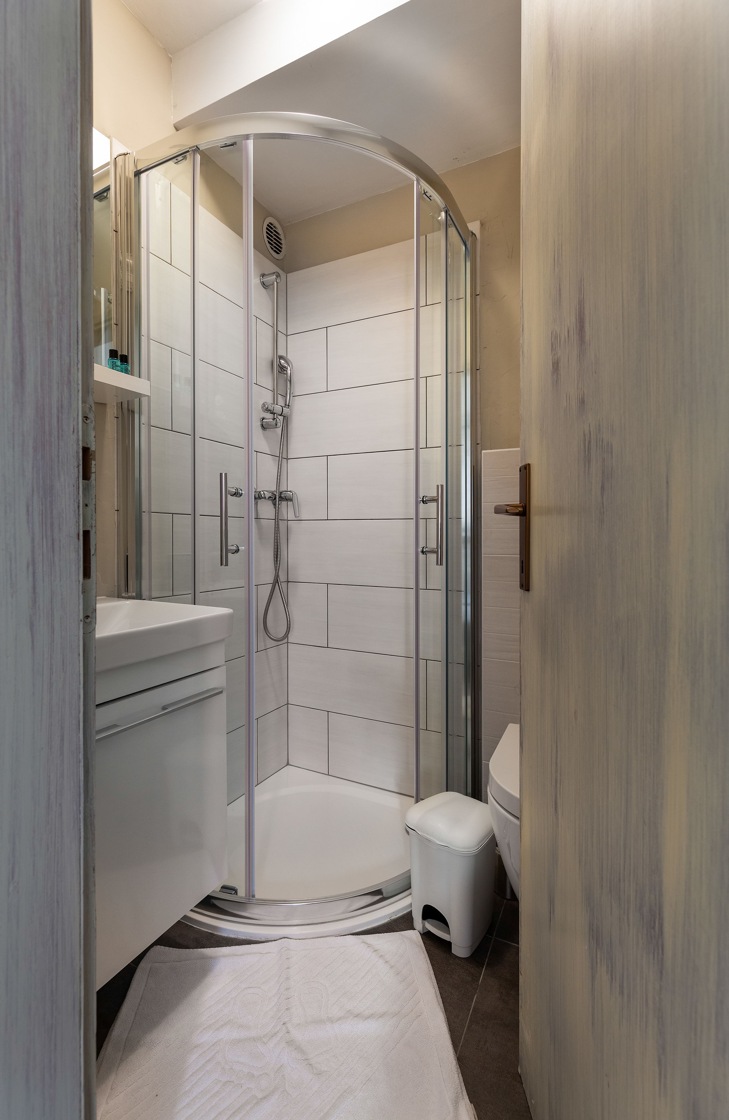 Un baño moderno con ducha envuelta en vidrio, un lavabo blanco y un inodoro.