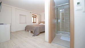 Un dormitorio con cama, mesita de noche, armario y zona de ducha.