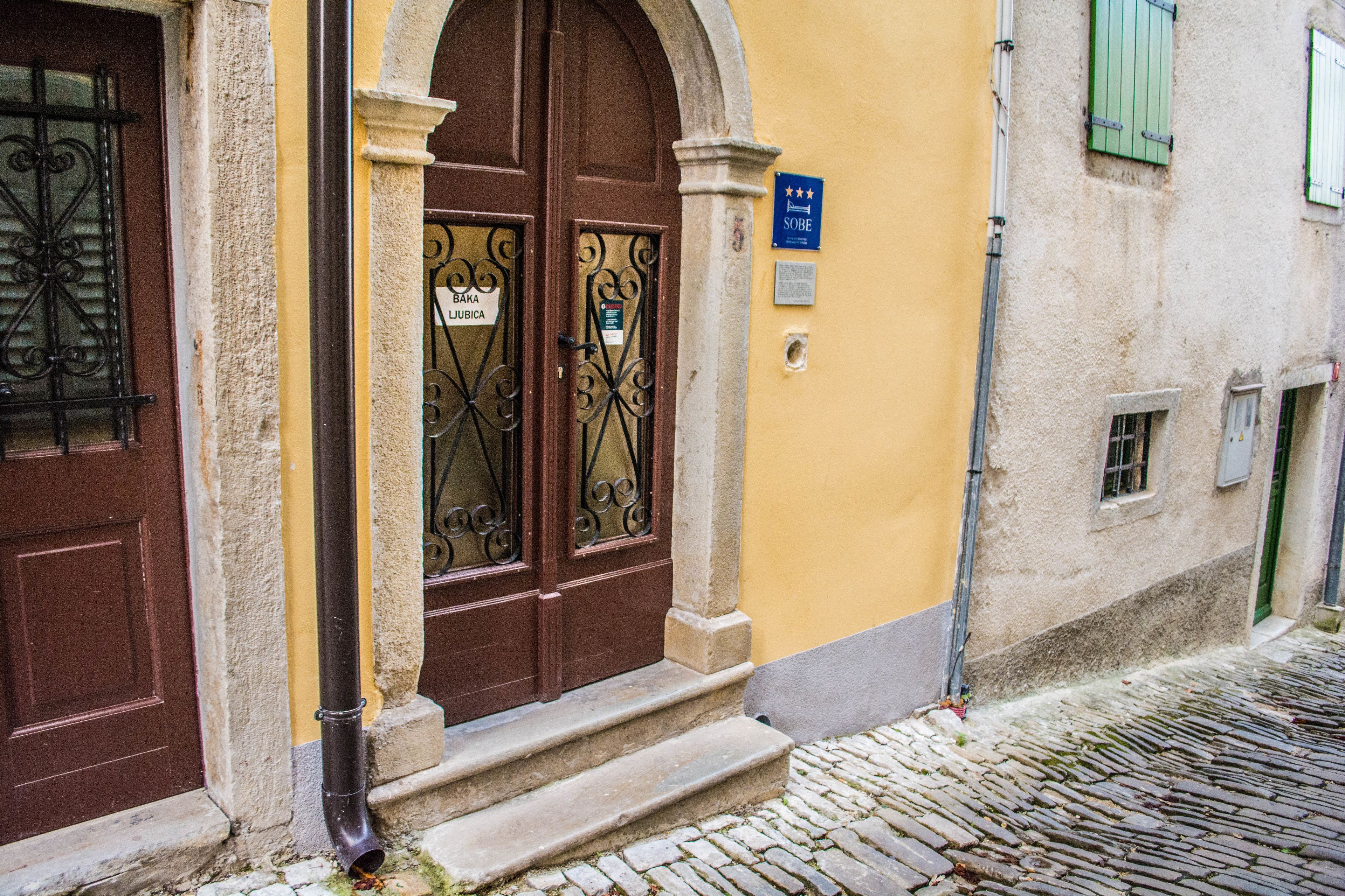 A building with a brown door, a plaque, and a cobblestone street.