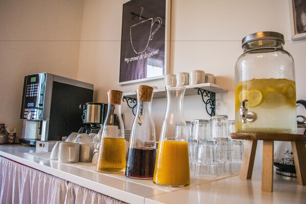 A breakfast bar with various beverages, a coffee machine, and a decorative coffee cup sign. - Villa Borgo B&B (Motovun)