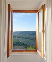 Una ventana con vistas a un paisaje que incluye campos y una carretera.