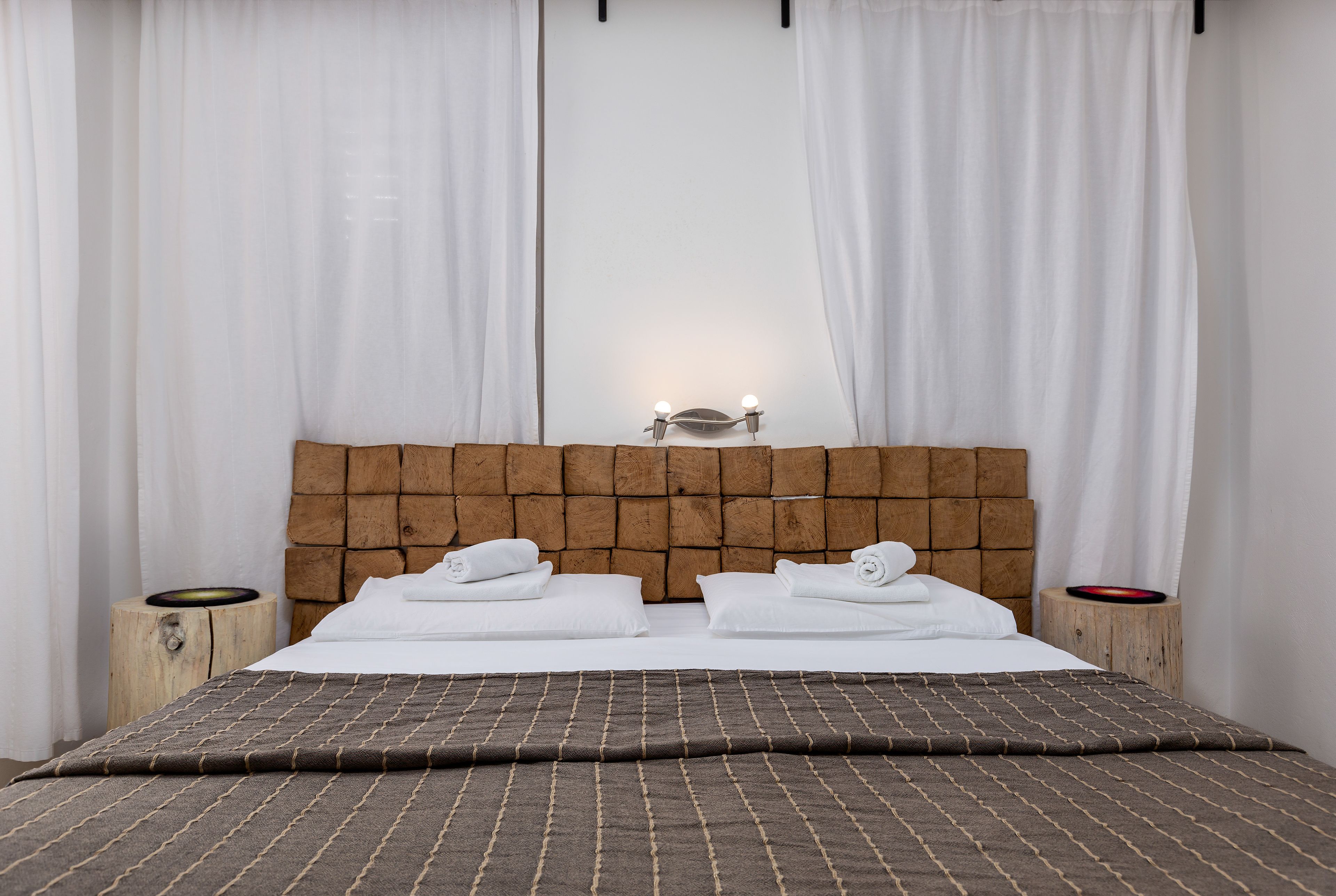 Un lit bien fait, avec une tête de lit marron, du linge de lit blanc et deux tables de chevet dotées de lampes.