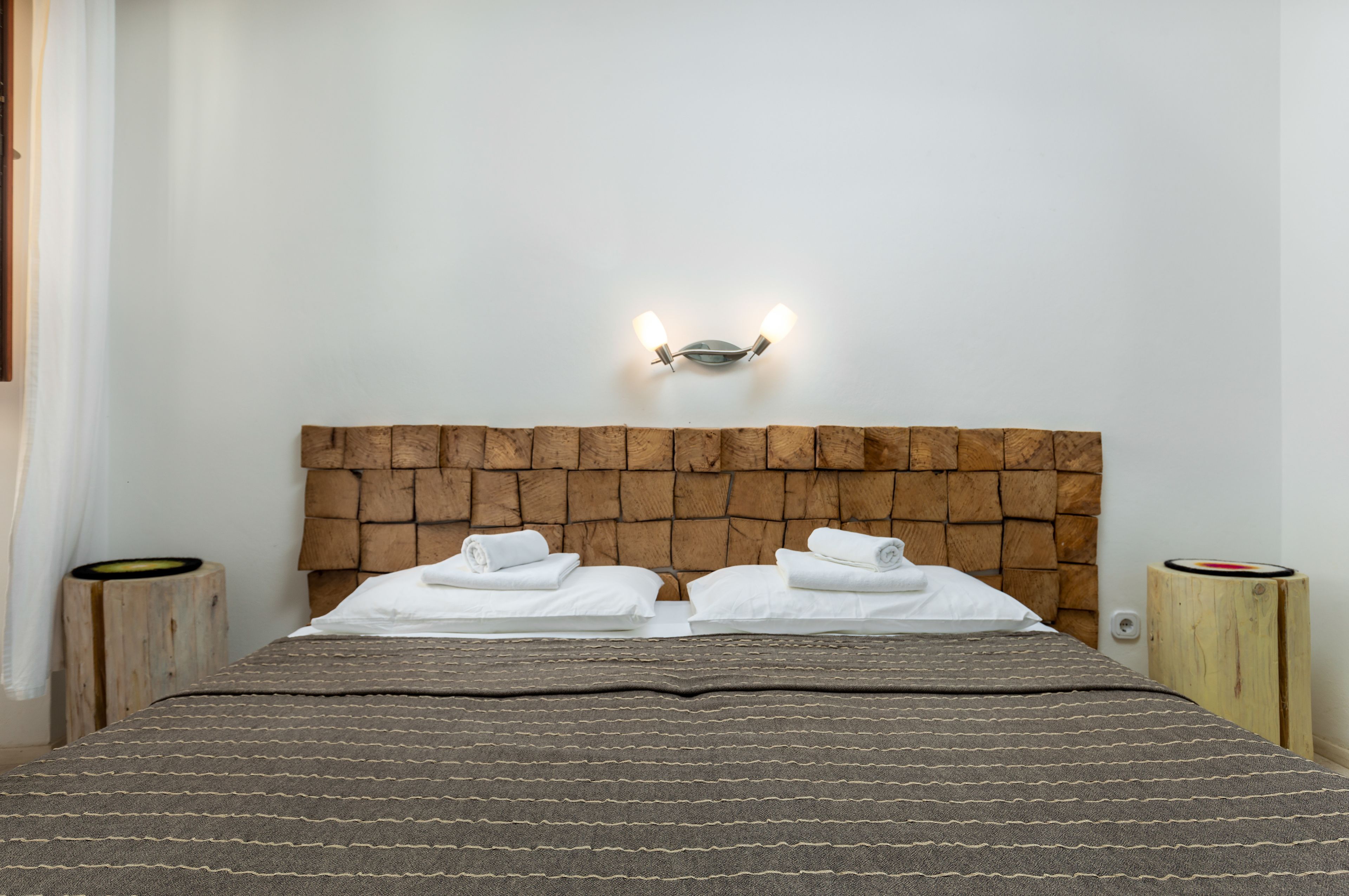 A neatly made bed with a patterned bedspread, a wooden headboard, and two bedside tables with lamps.