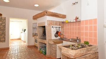 A kitchen with a brick oven, stone accents, and a tiled backsplash.