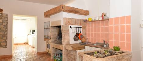 Una cocina con horno de ladrillo, detalles de piedra y salpicadero de azulejos.
