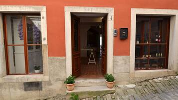 La entrada de un edificio con una puerta de madera, el número 4, y dos plantas en macetas en los escalones.
