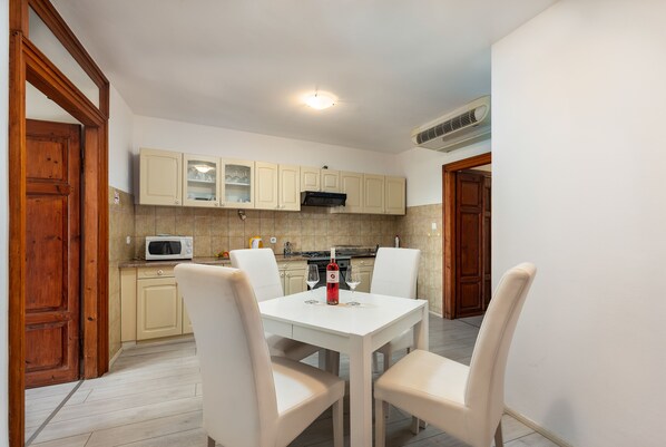 Una cocina funcional con una mesa blanca, armarios color beige y un microondas.