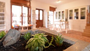 Una habitación con una maceta de piedra con suculentas, suelo de madera y vistas a un comedor con mesas y sillas.