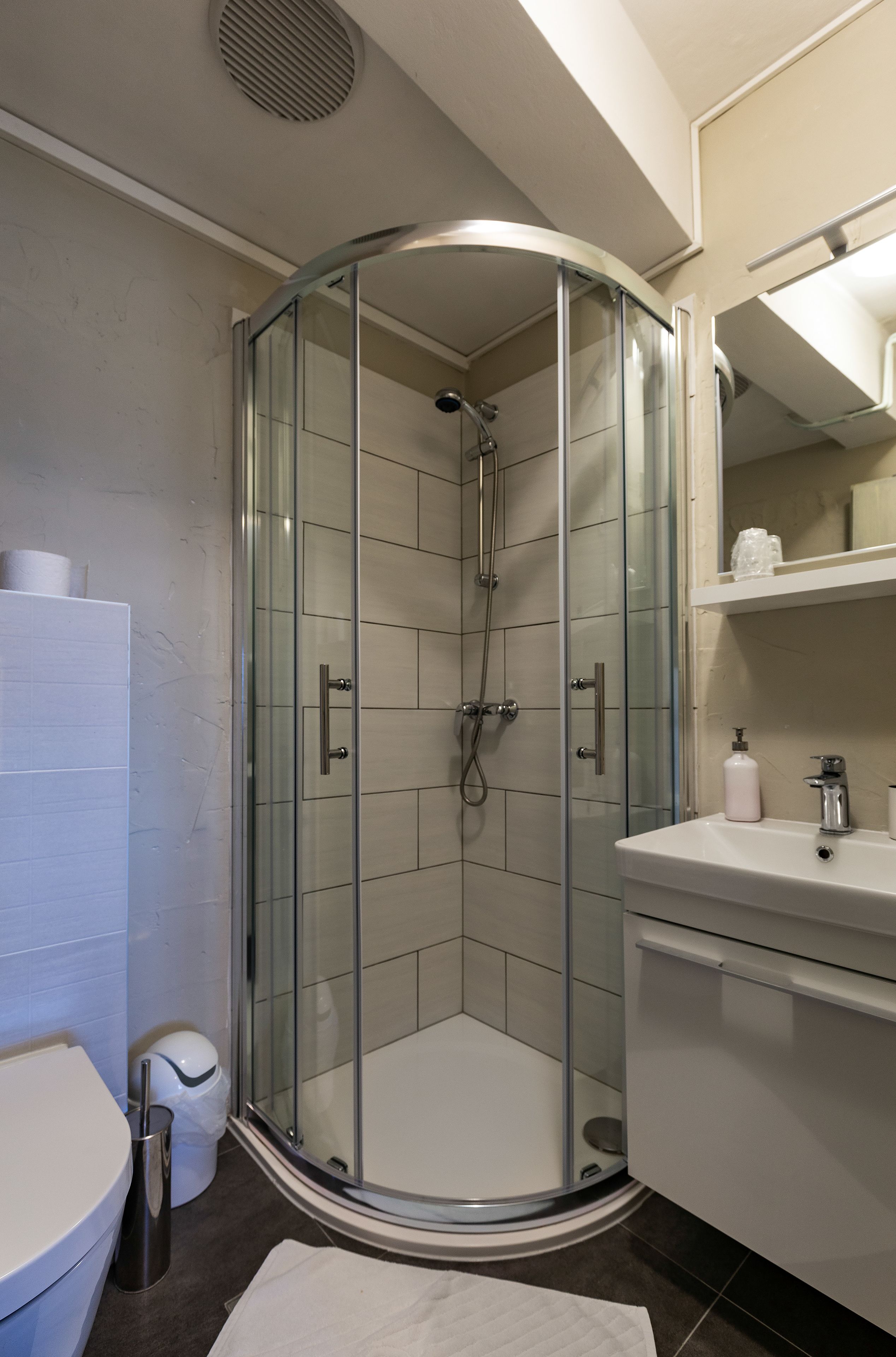 A modern bathroom with a glass-enclosed shower, a white sink, and a toilet.