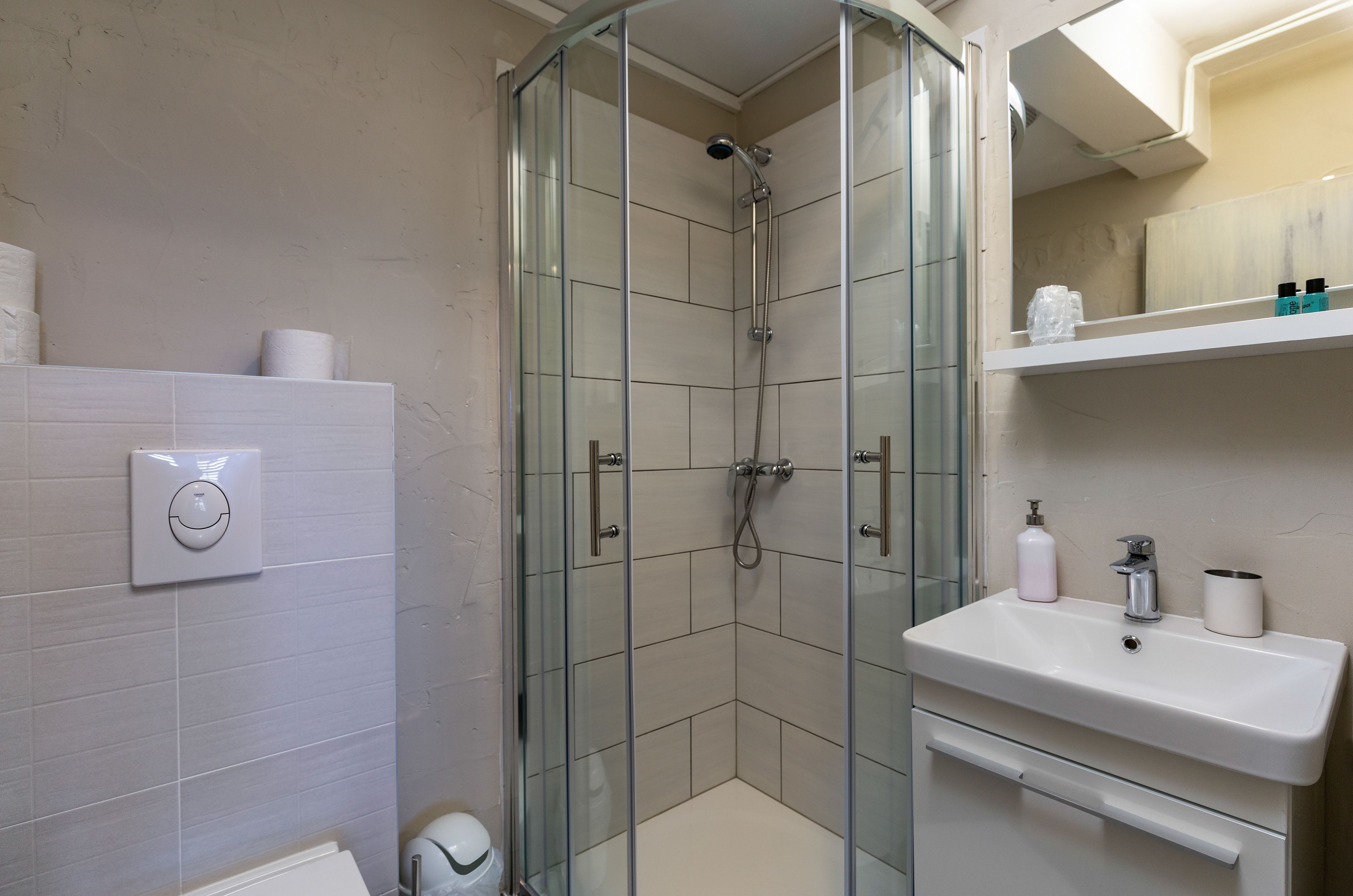 A modern bathroom with a glass-enclosed shower, a white sink, and a toilet.