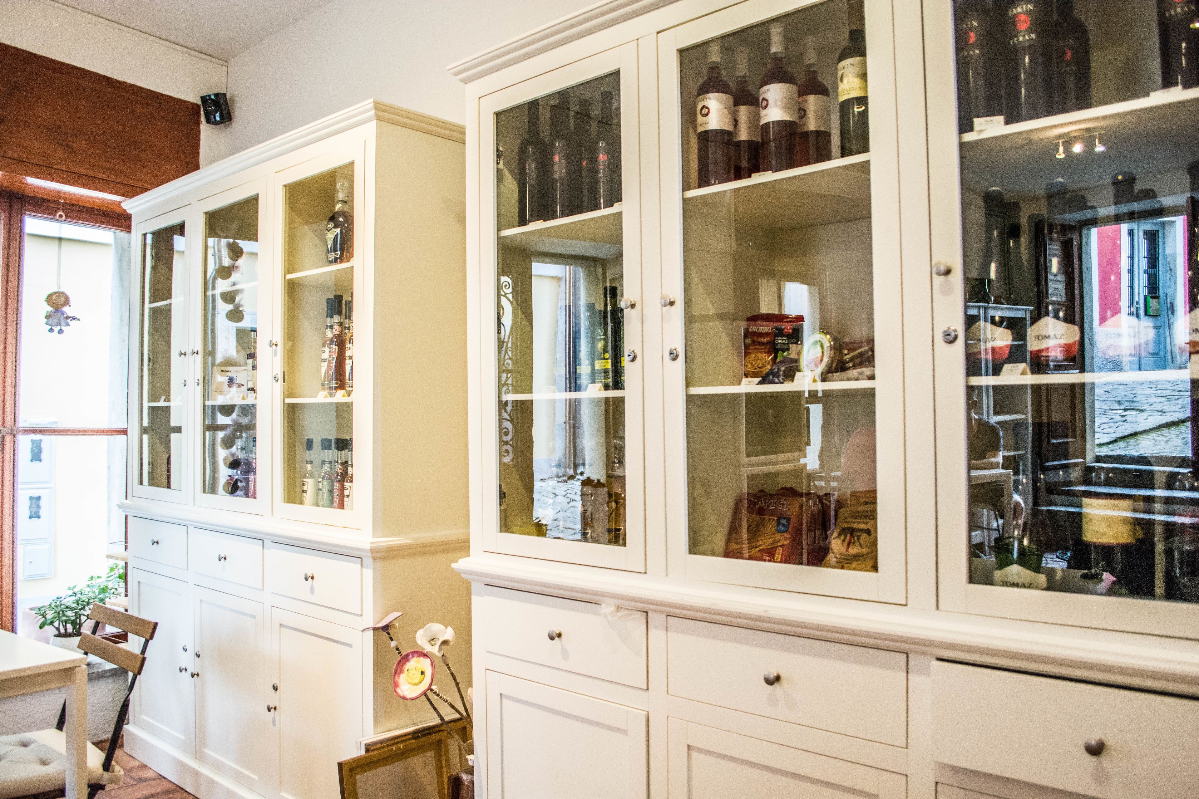 A room with white cabinetry containing various items, including bottles and decorative objects.