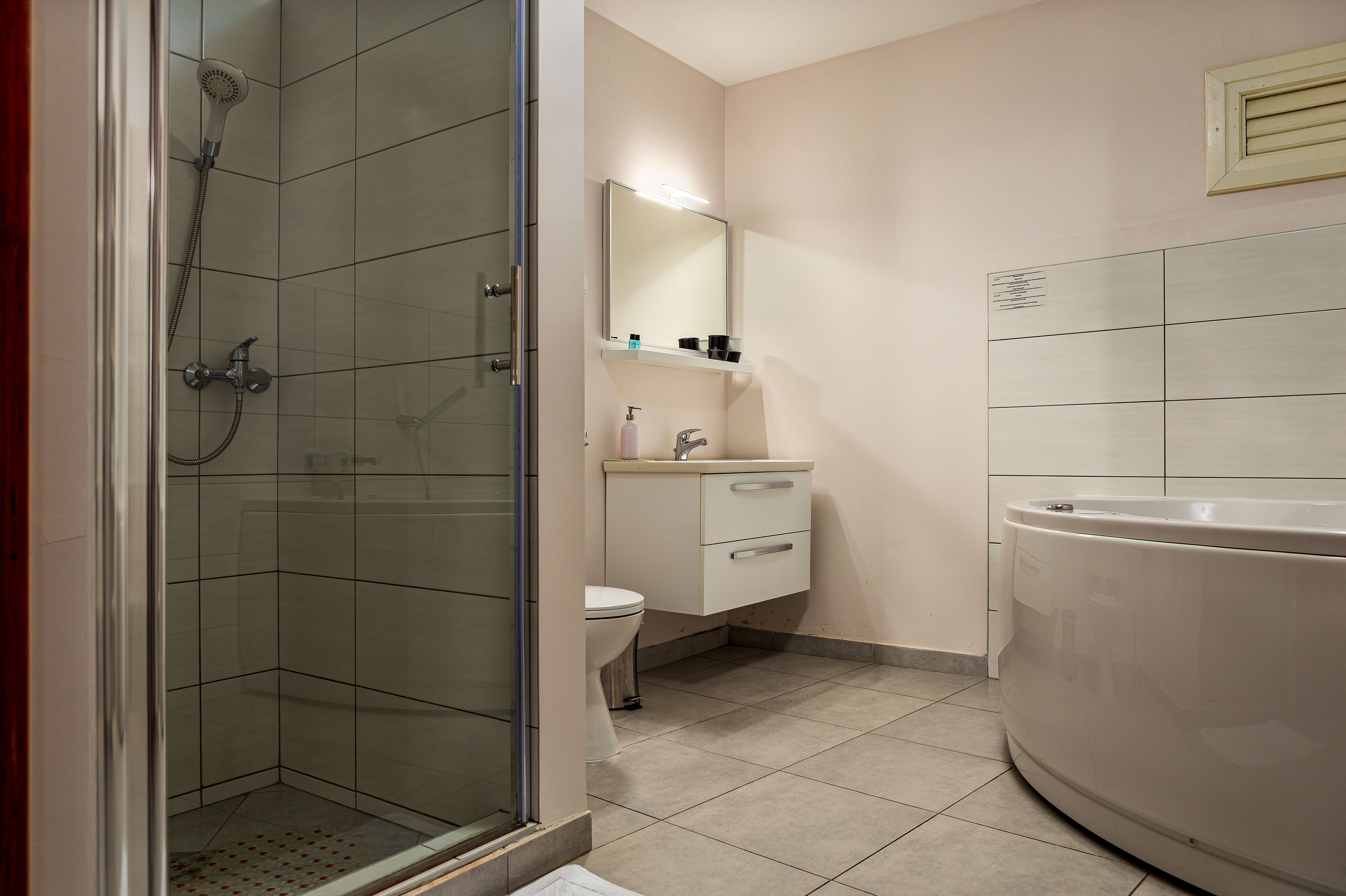 Un baño con ducha envuelta en vidrio, inodoro, lavamanos con espejo y bañera.