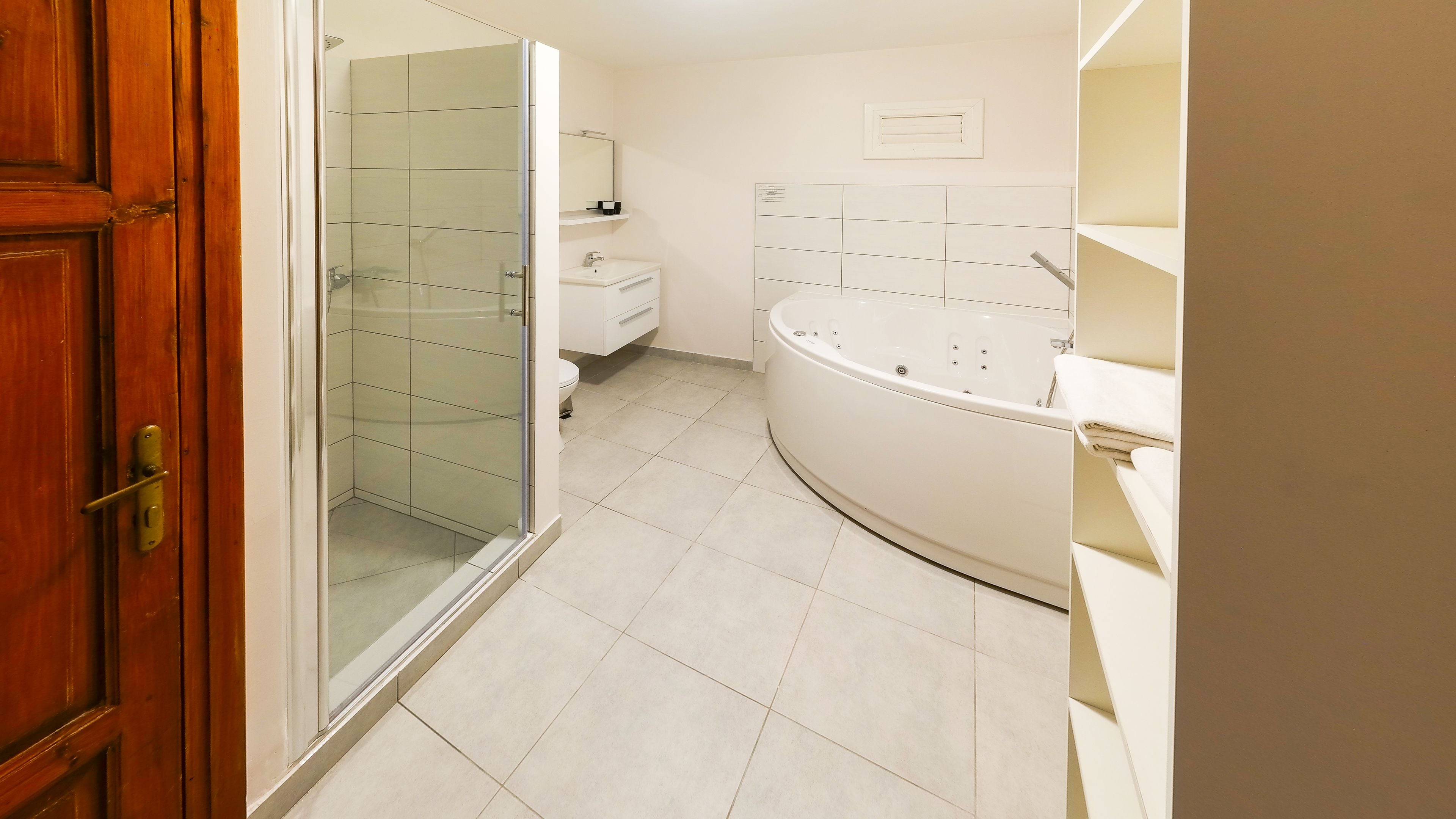 A bathroom with a glass shower enclosure, a white bathtub, and a toilet.