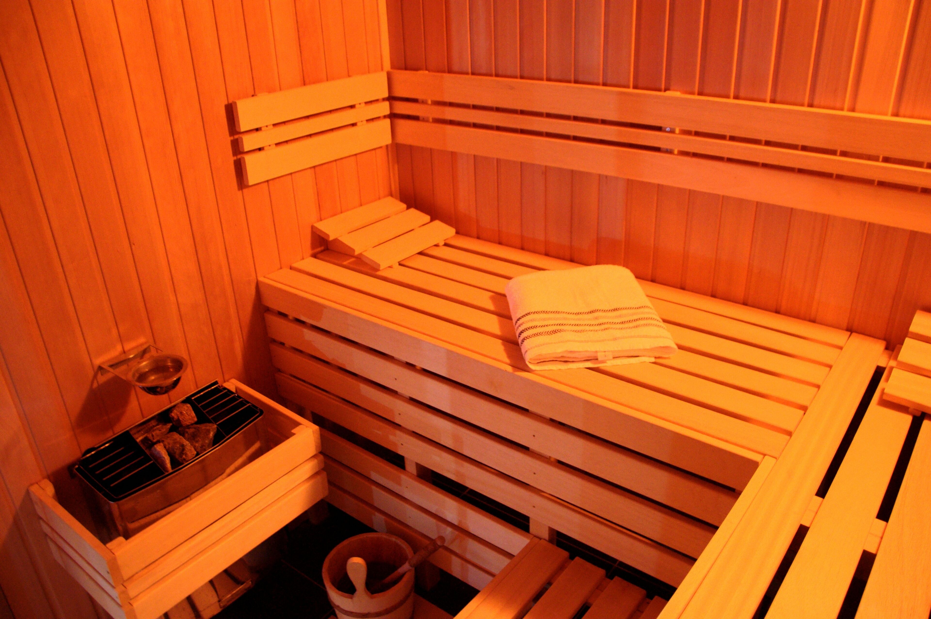 A sauna with wooden benches, a bench heater, and a towel on one of the benches.