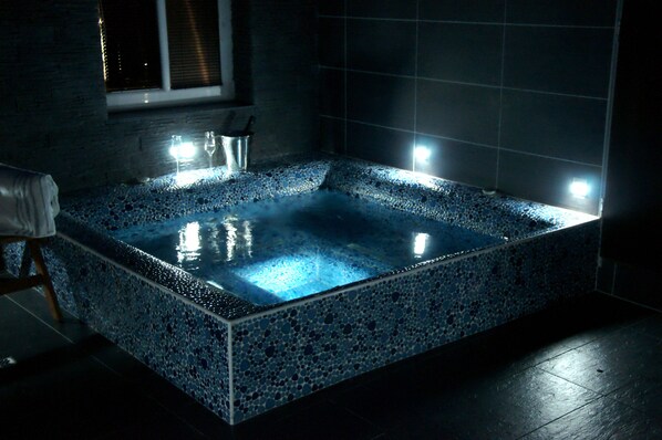 A rectangular hot tub with mosaic tile walls and floor, illuminated by spotlights. - Hotel Chata Orlik all inclusive (Pec pod Snezkou)