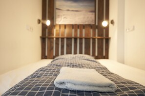 A neatly made bed with a checkered bedspread and a folded white towel. - Hotel Chata Orlik all inclusive (Pec pod Snezkou)