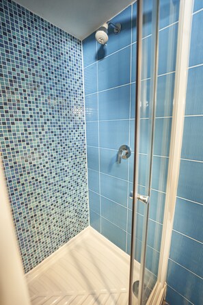 A bathroom with blue mosaic tiles, a glass shower enclosure, and a white bathtub. - Hotel Chata Orlik all inclusive (Pec pod Snezkou)