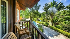 A wooden deck with a view of a lush garden and a large fan palm tree. - Vana Varin Resort Hua Hin (Hua Hin)
