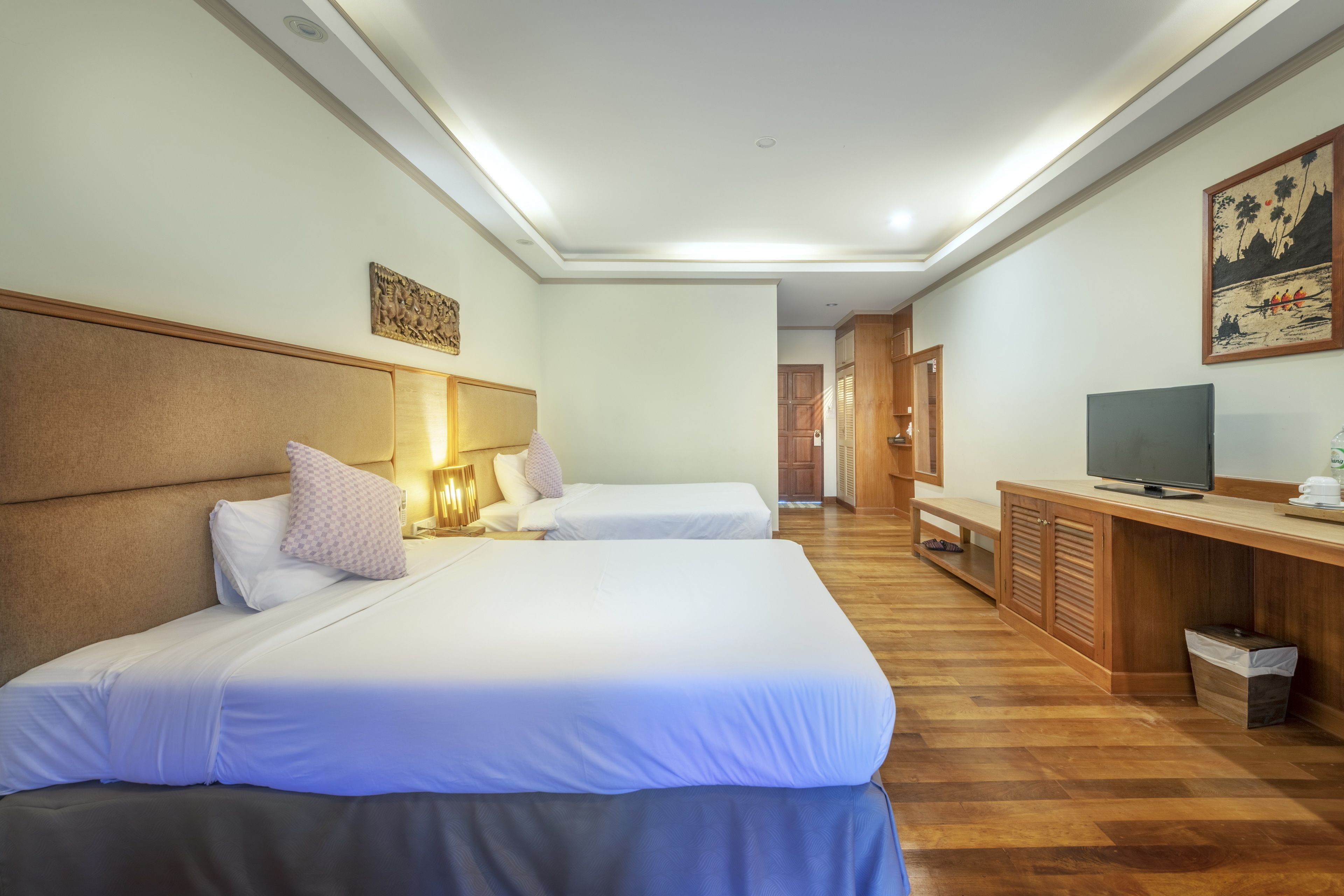 A hotel room with two beds, a TV, a desk, and a waste bin.