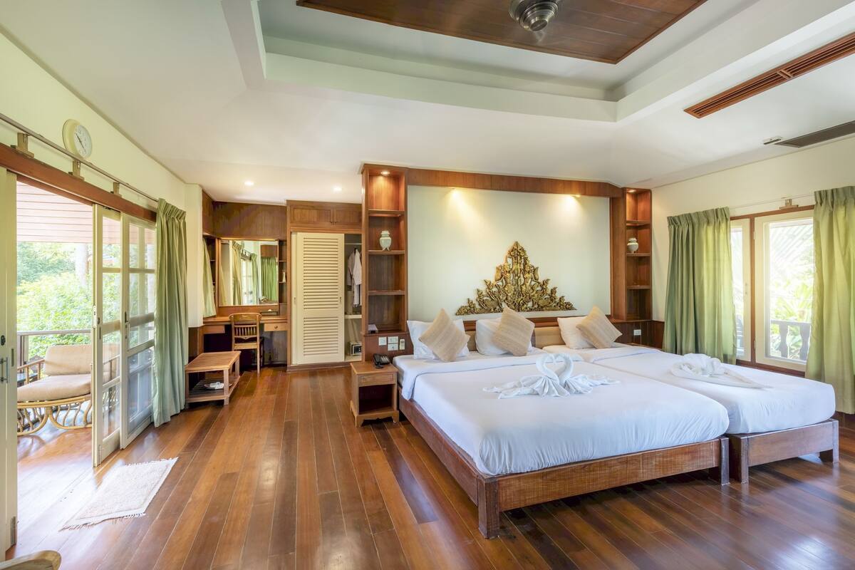Une chambre spacieuse avec un grand lit, des meubles en bois et une vue sur la verdure.