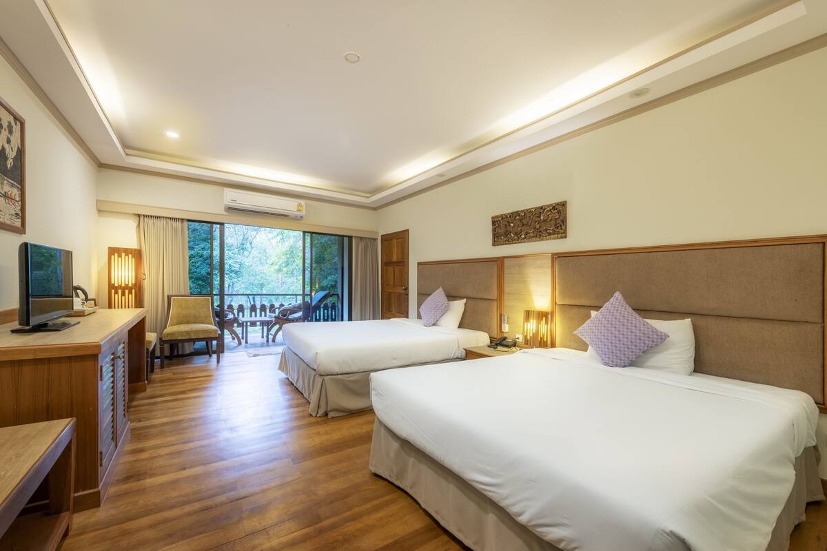 Une chambre d’hôtel avec deux lits, un bureau avec un ordinateur, une chaise et une vue sur l’extérieur.
