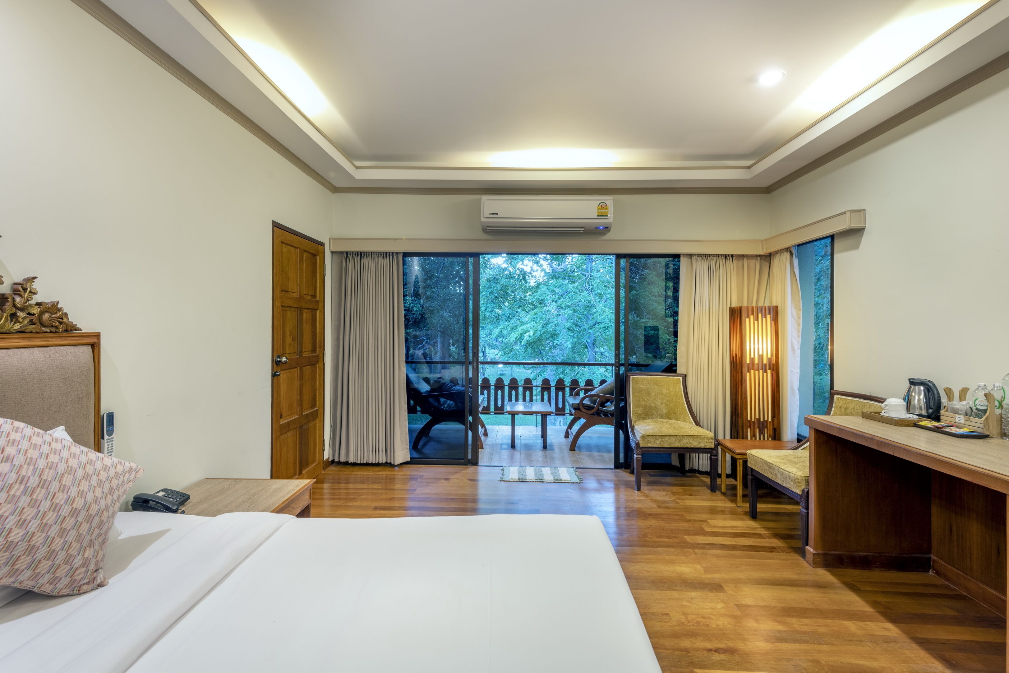 Une chambre d’hôtel équipée d’un lit, d’un bureau, d’une chaise et offrant une vue sur l’extérieur grâce à de grandes fenêtres.