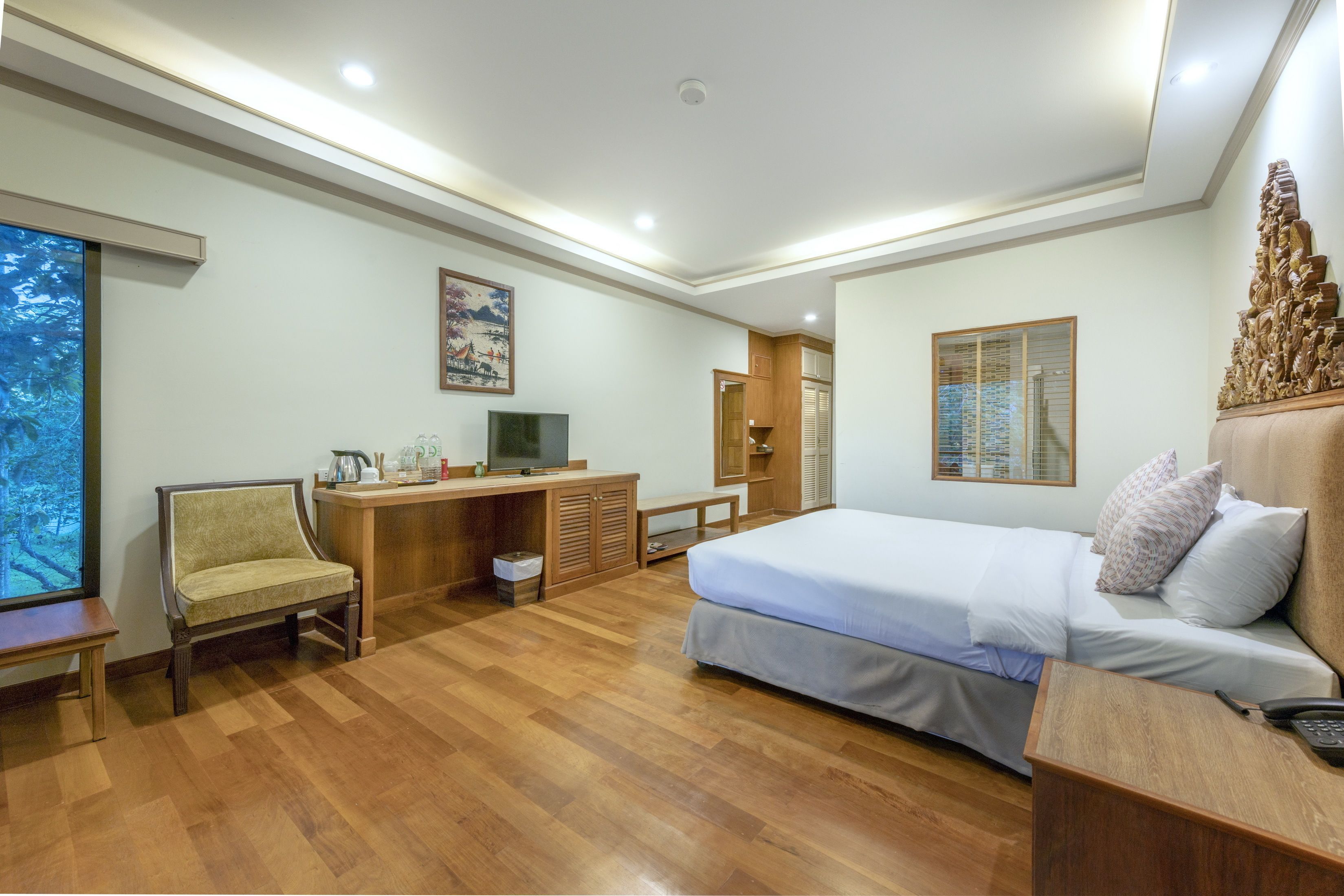A hotel room with a bed, desk, chair, and a television.