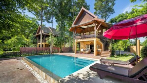 A poolside area with a wooden house, a red umbrella, and lounge chairs. - Vana Varin Resort Hua Hin (Hua Hin)