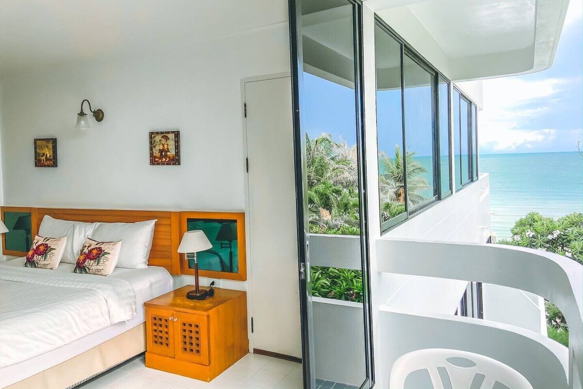 Ein Schlafzimmer mit Bett, Nachttisch und Blick auf den Ozean.