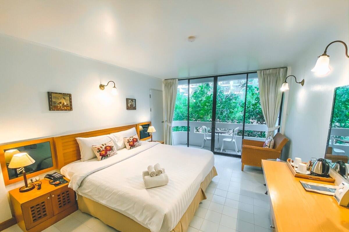Ein Hotelzimmer mit einem großen Bett, einem Schreibtisch mit Telefon und Blick ins Freie.