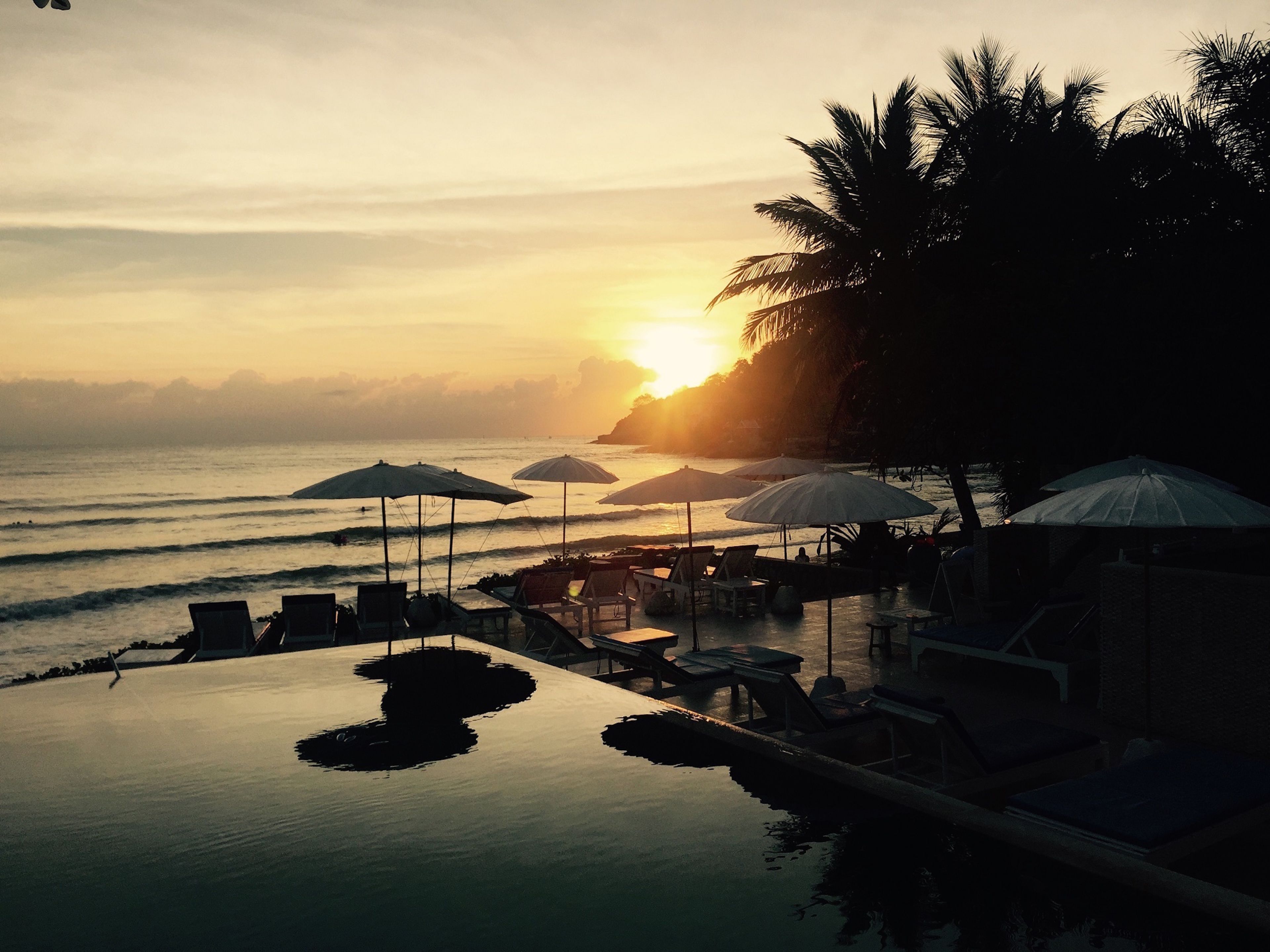 Una piscina al aire libre, sombrillas, sillones reclinables de piscina