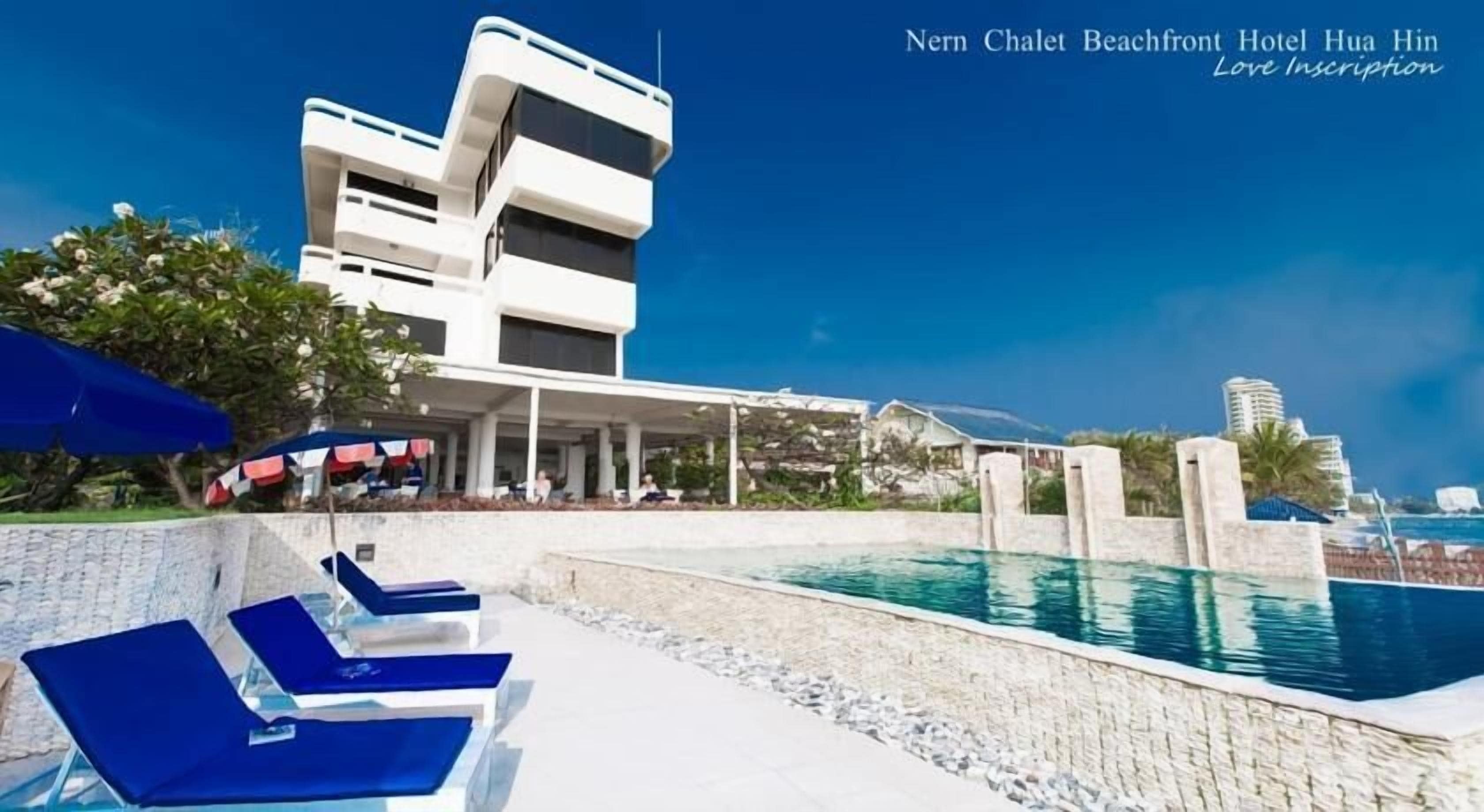 A modern hotel with a pool area, lounge chairs, and a view of the beach.