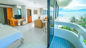 Ein Hotelzimmer mit Balkon, einem Bett, einem Schreibtisch mit Fernseher und Blick auf den Ozean.