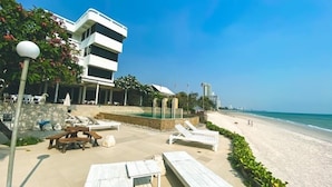 Ein Strandhotel mit Pool, Liegestühlen und freiem Blick auf das Meer.