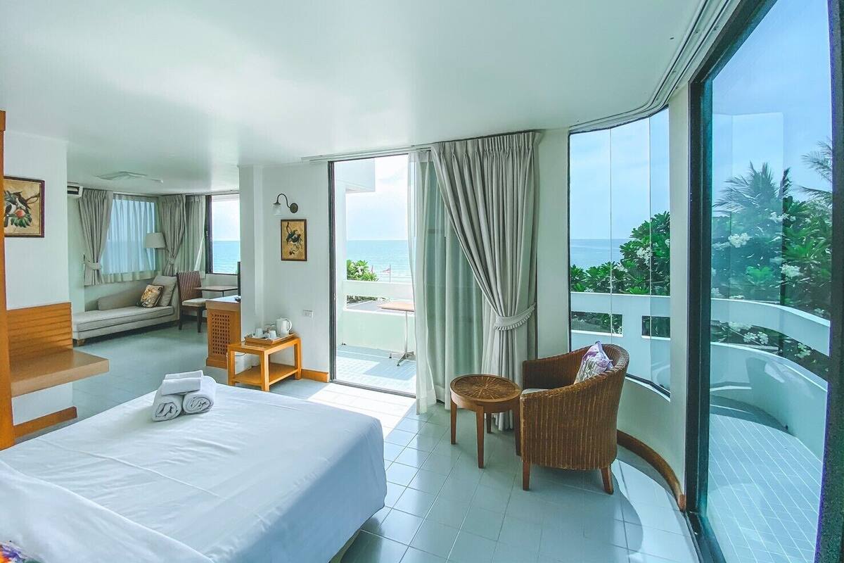 Ein Hotelzimmer mit Bett, kleinem Tisch, Stuhl und einem Balkon mit Meerblick.