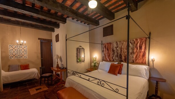 A bedroom with a four-poster bed, a bench, a small table, and a chair. - El Beaterio (Santo Domingo)