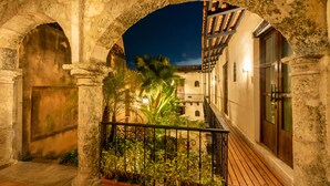 An outdoor courtyard with stone arches, a wooden deck, and potted plants. - El Beaterio (Santo Domingo)