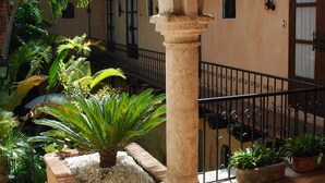 A courtyard with a wooden bench, potted plants, and a stone archway. - El Beaterio (Santo Domingo)