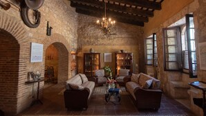 A rustic interior with exposed brick walls, wooden beams, and a chandelier. Furnishings include two sofas and a coffee table. - El Beaterio (Santo Domingo)