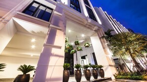 A modern hotel entrance with a white facade, large columns, and hanging plants. - Mövenpick Hotel Sukhumvit 15 Bangkok (Bangkok)