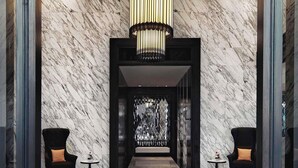 A marble lobby with a geometric patterned floor, a central chandelier, and two armchairs with small tables. - Mövenpick Hotel Sukhumvit 15 Bangkok (Bangkok)
