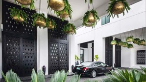 A modern building with a black car parked in front, large windows, and hanging planters with greenery. - Mövenpick Hotel Sukhumvit 15 Bangkok (Bangkok)