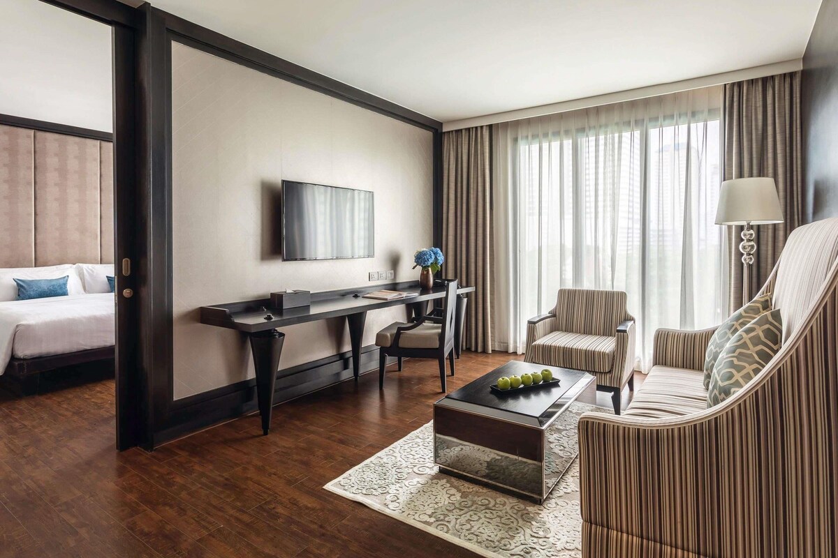 A hotel room with a bed, a desk, a TV, a coffee table, and a sofa.