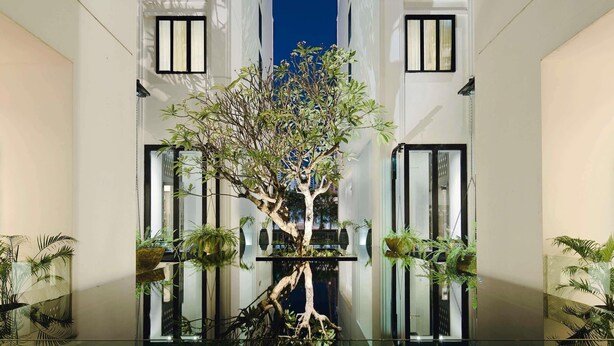 A modern building with a central tree, large windows, and indoor plants. - Mövenpick Hotel Sukhumvit 15 Bangkok (Bangkok)