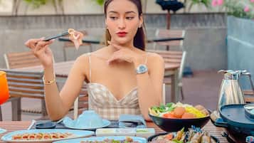 A dining table with various dishes, a teapot, and a person eating with chopsticks.